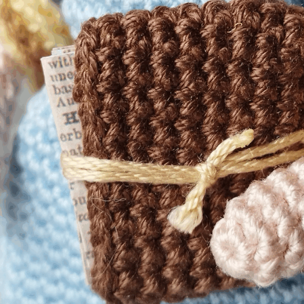 Detalle de libro tejido a crochet que lleva el amigurumi de Jane Austen.