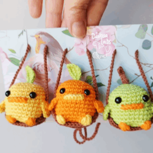 Tres pollos tejido con crochet sobre un hilo que se balancea