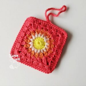 Funda crochet para airpods de color rojo con una flor en el centro