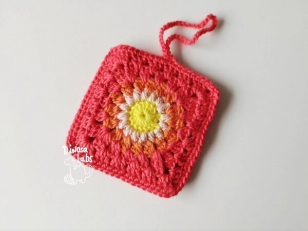 Funda crochet para airpods de color rojo con una flor en el centro